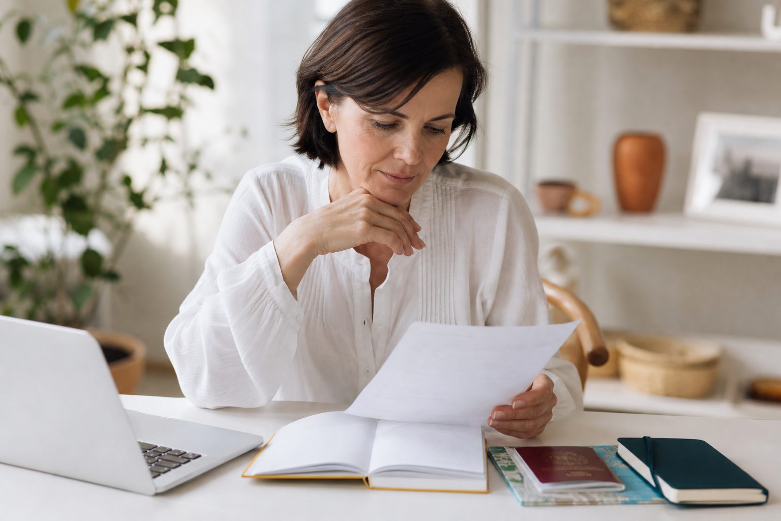 Trip organizer reviewing a deposit budget at a bright white desk with a passport and laptop